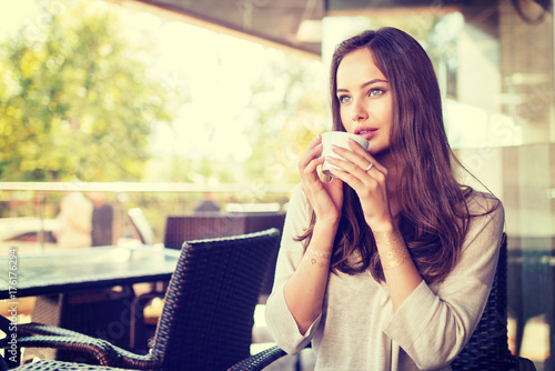 beautiful young girl sitting alone in a cafe drinks coffee