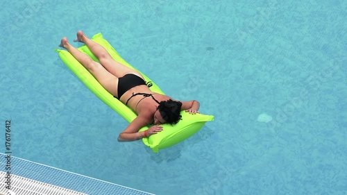 Girl swims in the pool on a green inflatable mattress photo
