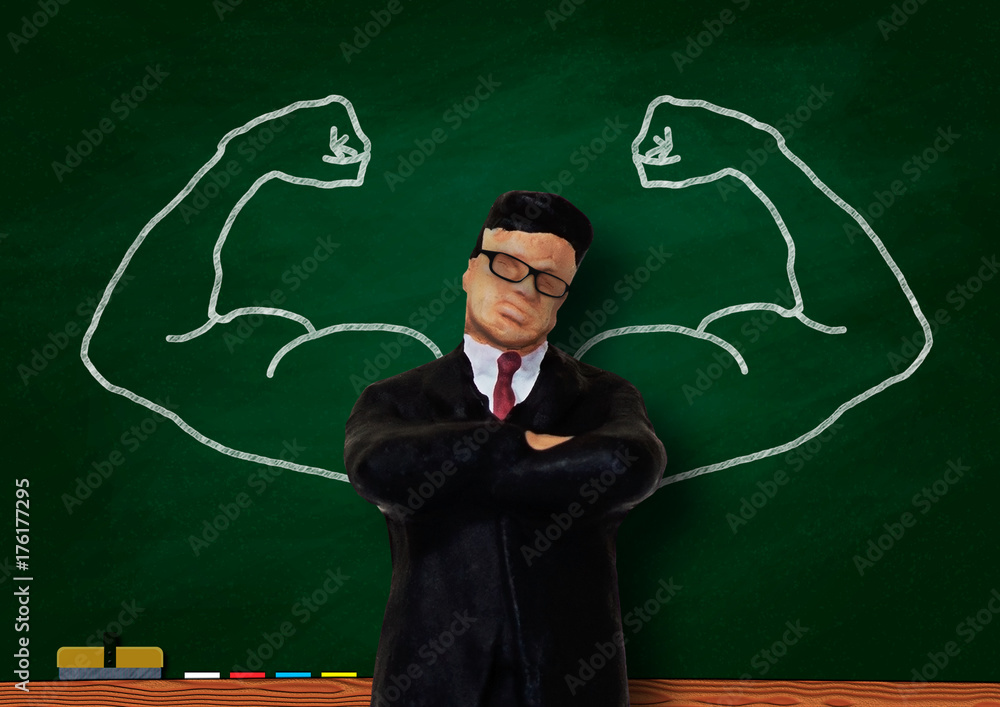 黒板に描いた筋肉質の腕とビジネスマン模型