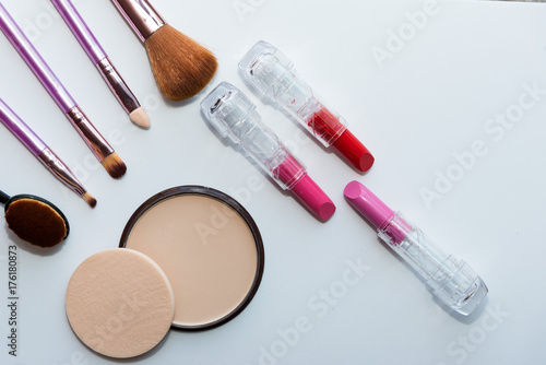 A collection of make up and cosmetic beauty products arranged on a light purple background, with empty space at side