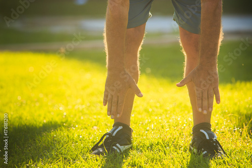 Legs of Man Doing Morning Exercises Touching Feet on Lawn