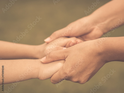 Retro woman  holds the hand of a lovely child. Mother and son holding hands in the background of the green field. People, charity and family concept. © Siam