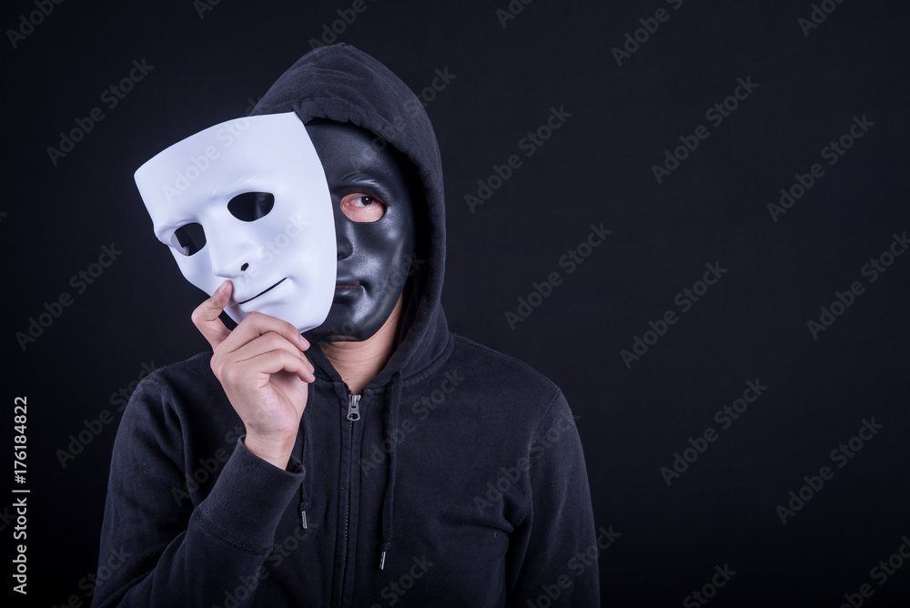 Mystery man wearing black mask holding white mask. Anonymous social masking  or halloween concept. Stock Photo | Adobe Stock