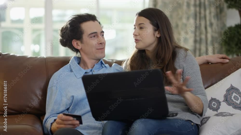 Cheerful couple with laptop & credit card shopping online at home Cheerful couple with laptop & credit card shopping online at home