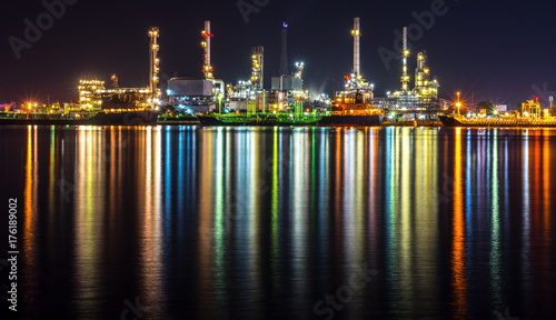 Oil refinery, tanker ship and petrochemical plant at night beside Chao Phaya river, Thailand. Colorful light reflection.
