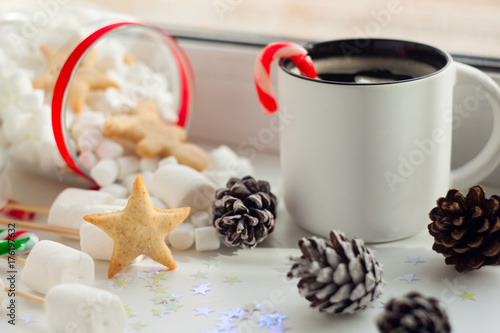 New year preparation concept. Christmas background with ginger bread, cup of coffee, red christmas candy cane, cones, marshmallow. New Year composition of festive breakfast