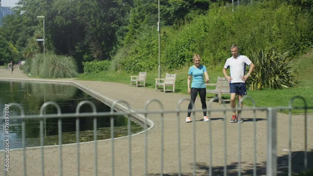 Healthy mature man & woman stop to take a break from running in the park Healthy mature man & woman stop to take a break from running in the park