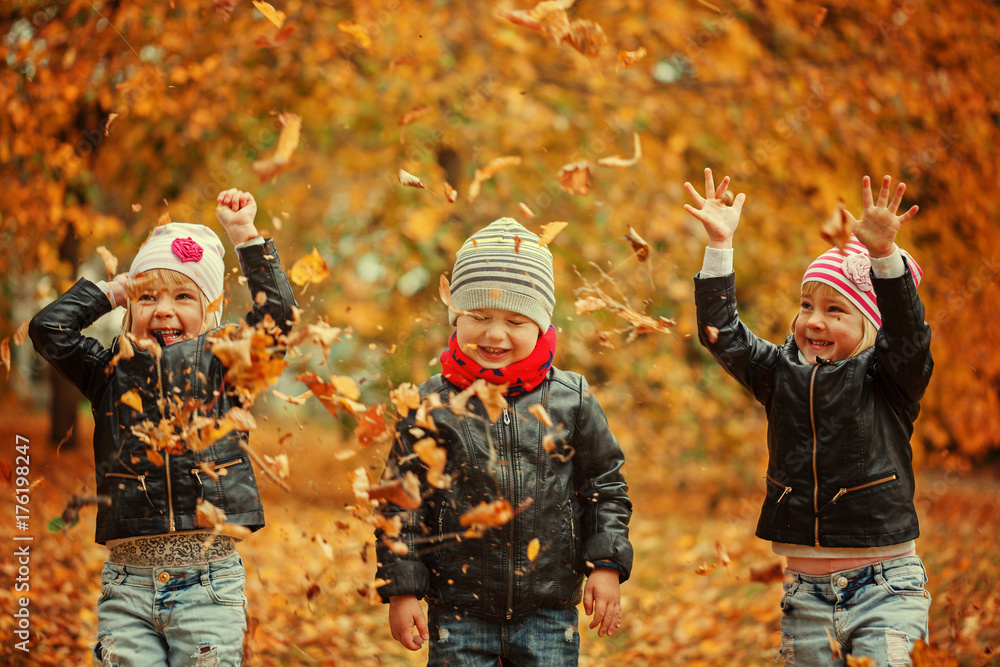 Happy kids having fun with leaves in autumn park Stock Photo | Adobe Stock