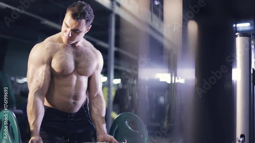Brutal athletic men lifts the barbell in gym