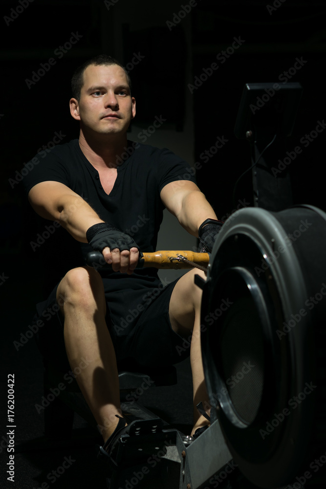 Fototapeta premium training on a cardio boating machine. against a dark background