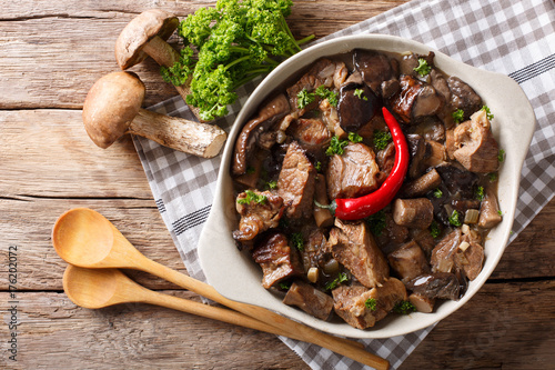 Delicious food: beef stew with wild mushrooms in spicy sauce close-up in a bowl. Horizontal top view