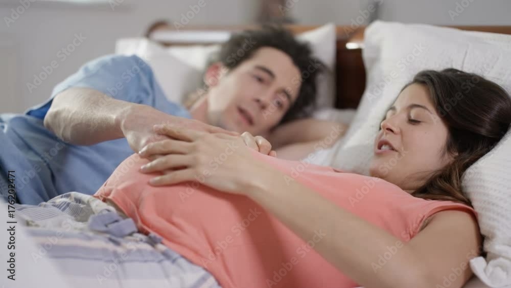 Happy couple expecting a baby relaxing together in bed Happy couple expecting a baby relaxing together in bed
