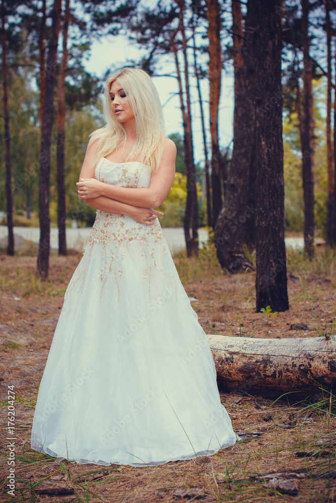 Modern stylish bride at the evening forest. Bride at countryside next to old trees in a pine forest at autumn. Wedding in forest.