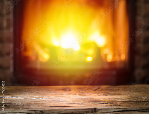 Old wooden table and fireplace with warm fire on the background.