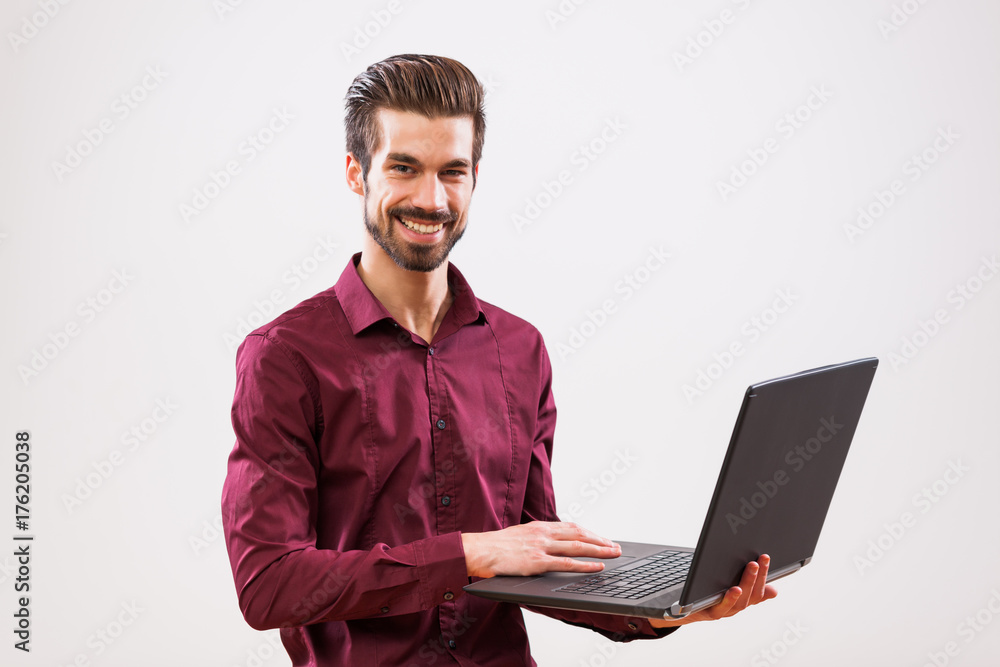Studio shot portrait of young successful businessman who is using laptop. Studio shot portrait of young successful businessman who is using laptop.