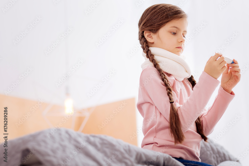 Curious girl measuring the temperature while sitting on the bed Curious girl measuring the temperature while sitting on the bed
