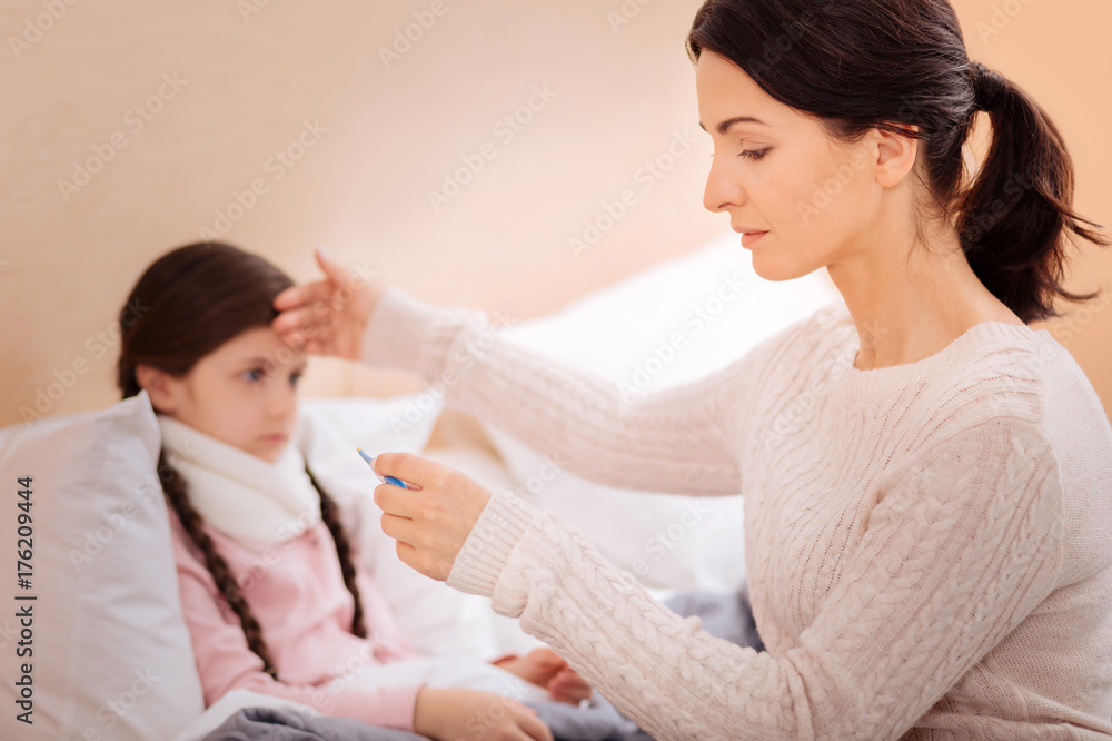 Caring mother measuring the temperature of her child