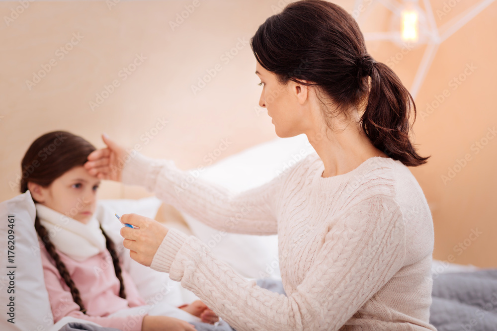 Loving mother checking the temperature of her ill daughter Loving mother checking the temperature of her ill daughter