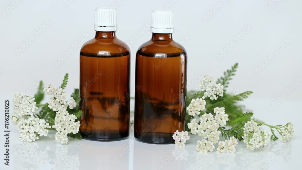 yarrow oil in two brown glass bottles and yarrow flowers on a light background. Natural pharmacy yarrow oil in two brown glass bottles and yarrow flowers on a light background. Natural pharmacy