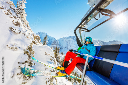 Skier sitting at ski lift in high mountains during sunny day