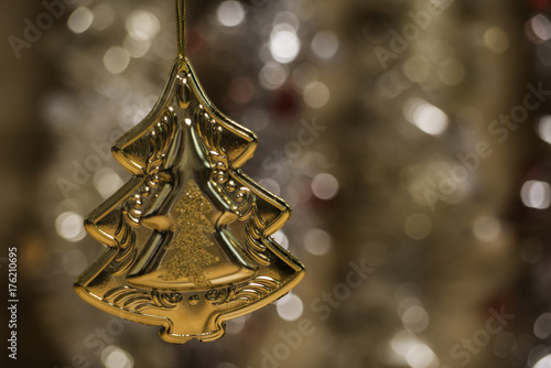 golden pine tree hanging on Christmas ornament with glowing blurred background