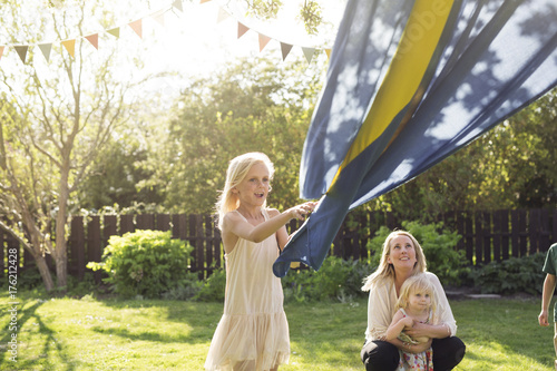 Mother with child (18-23 months) watching her daughter (8-9) holding Swedish flag photo