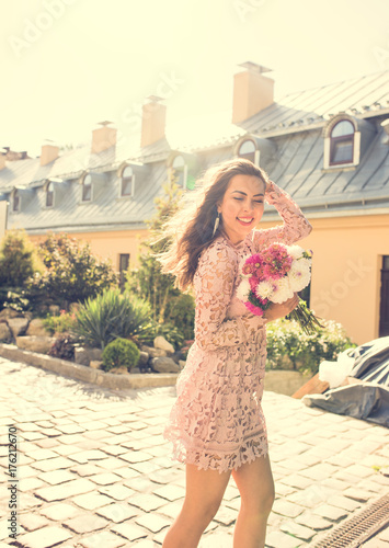 Elegant smiling model posing with flowers in rays of light. Vintage toning