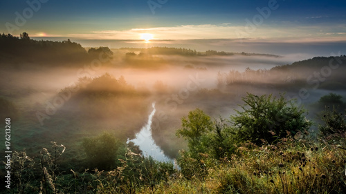 Wonderful dawn at foggy valley in autumn
