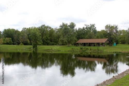 The lake and the picnic shelter in the park on a cloudy day.