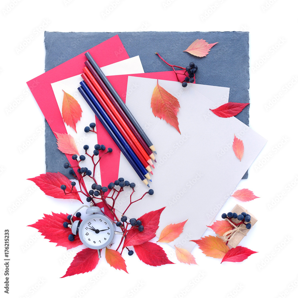 Fototapeta premium Autumn background with an alarm clock, pencils, sheets of paper and autumn leaves. Top view. Space for your text.