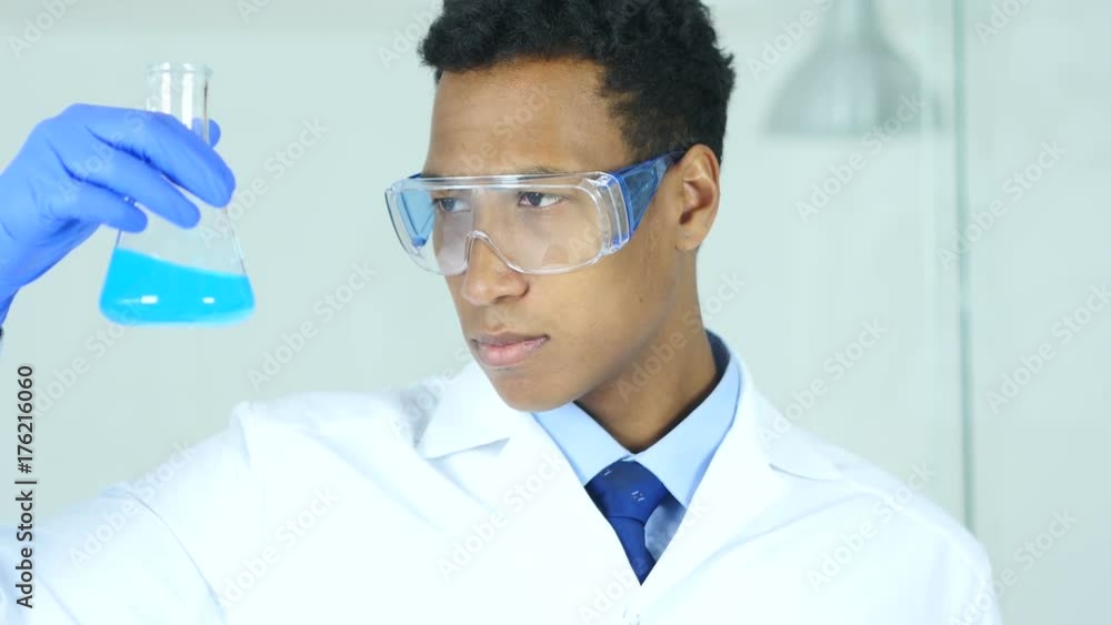 Scientist, Doctor Looking at Blue Solution in Flask in Laboratory Scientist, Doctor Looking at Blue Solution in Flask in Laboratory