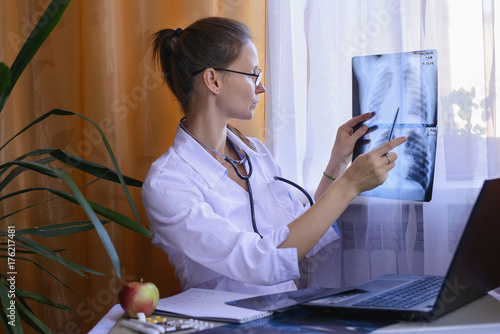 врач внимательно изучает рентгеновский снимок в кабинете поликлиники