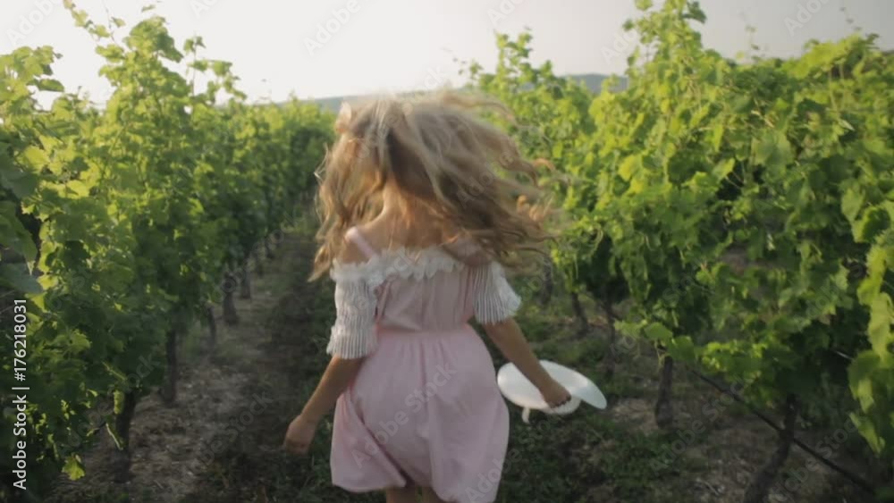 Free girl runs along the grass between vineyards Free girl runs along the grass between vineyards