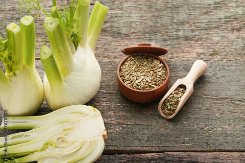 Ripe fennel bulbs and dry seeds in bowl on wooden table