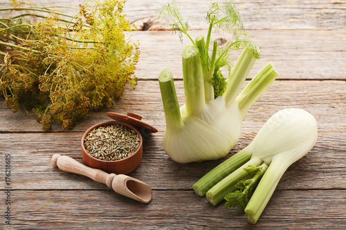 Ripe fennel bulbs and dry seeds in bowl on grey wooden table