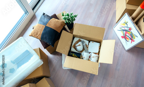 Large living room with stack of moving boxes and open kitchenware box