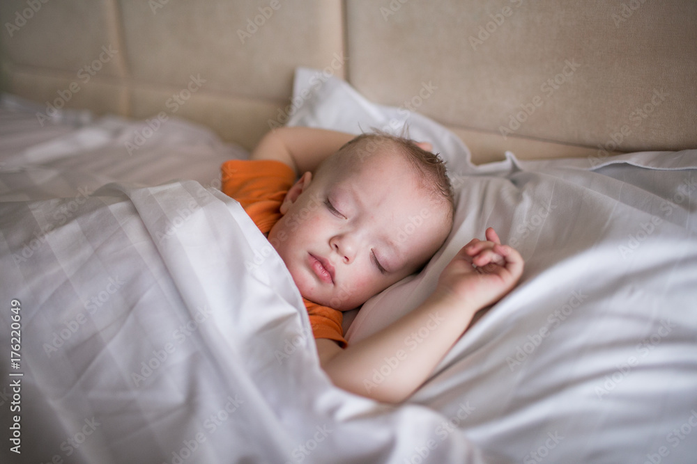 Little boy in an orange t-shirt is sleeping Little boy in an orange t-shirt is sleeping