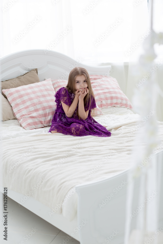 Sweet girl in purple dress in bed with cushins Sweet girl in purple dress in bed with cushins