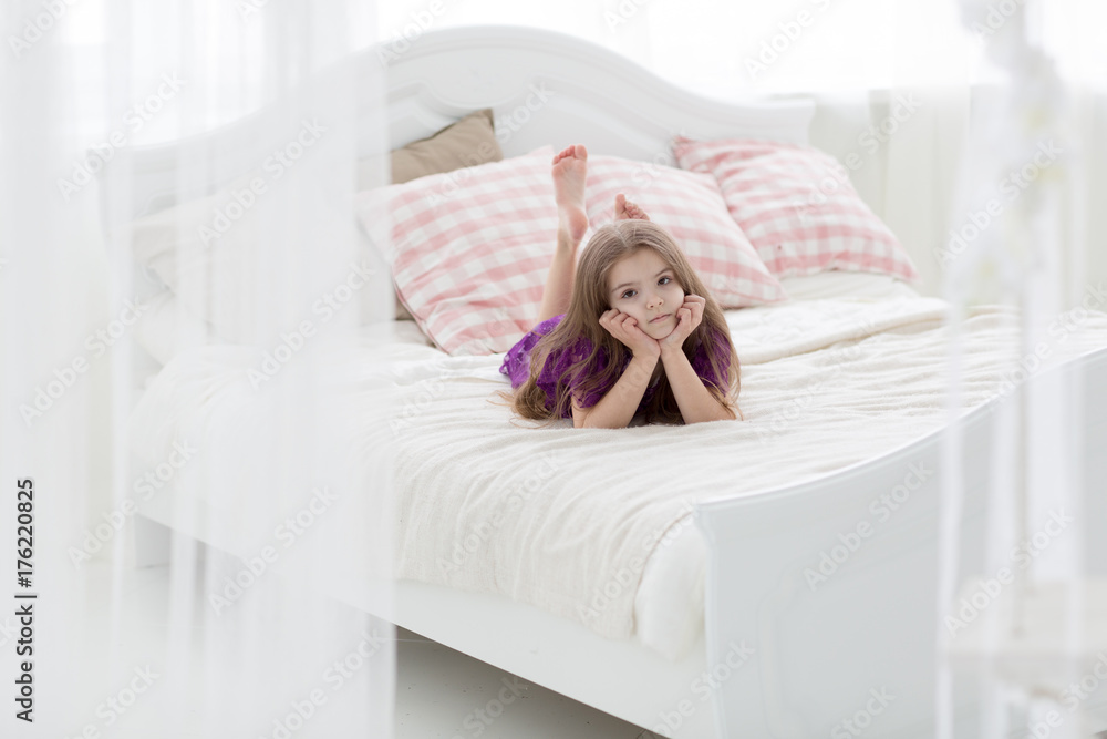 Sweet girl in purple dress in bed with cushins Sweet girl in purple dress in bed with cushins