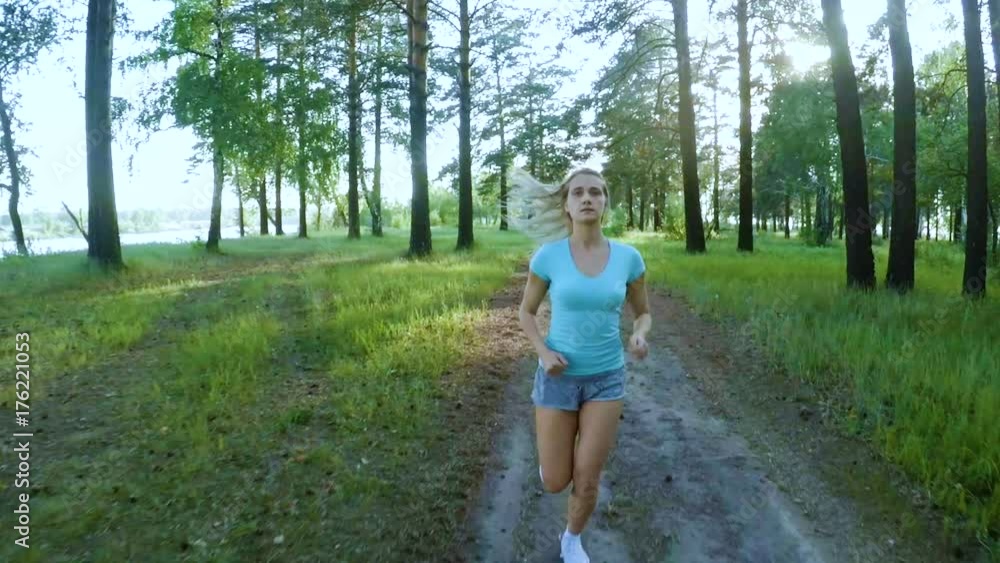 Pretty sporty girl jogging on a forest trail. Pretty sporty girl jogging on a forest trail.