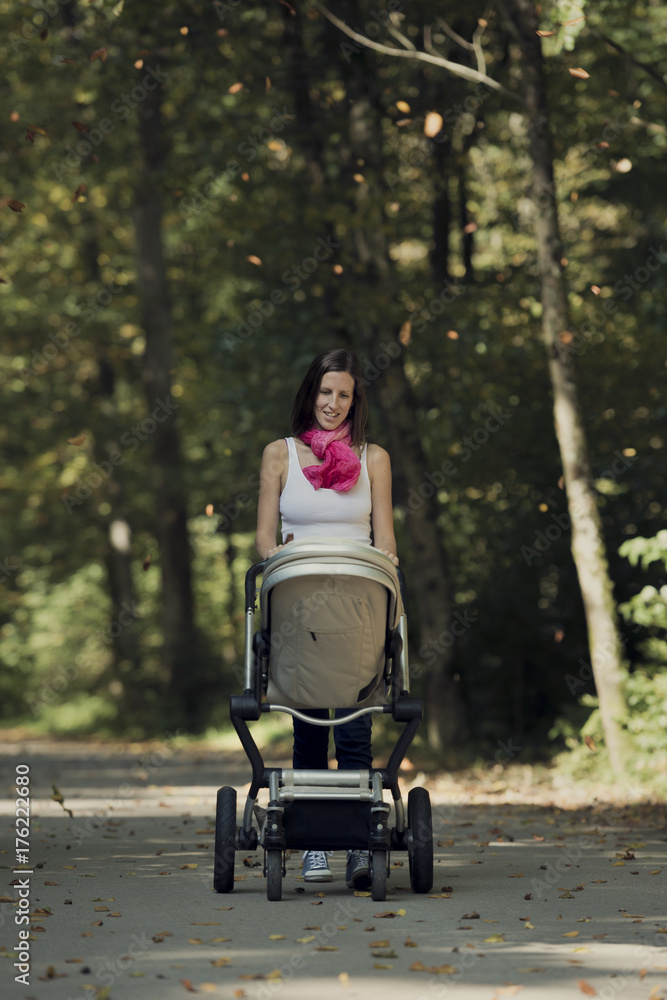 Attractive stylish woman pushing a baby stroller Attractive stylish woman pushing a baby stroller