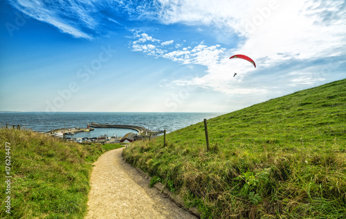 Hill pathway to the sea and parachuting man