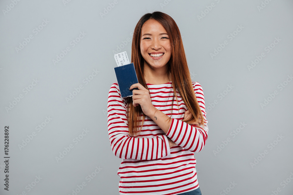 Happy asian woman in sweater holding passport with tickets Happy asian woman in sweater holding passport with tickets
