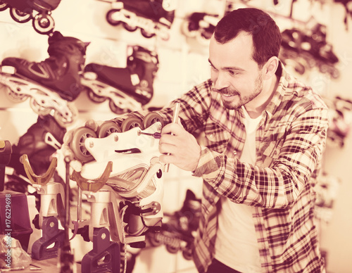 Male master fixing roller-skates in sports store