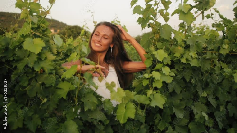 Portrait of the smiling girl between the vineyard leaves