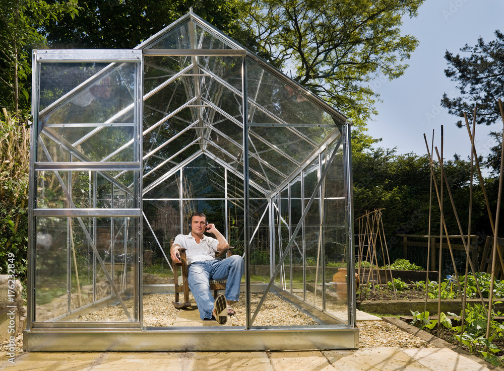 Man relaxing in greenhouse with music