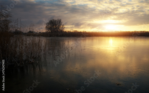 Winter landscape with frozen river and sunset sky. Composition of nature.