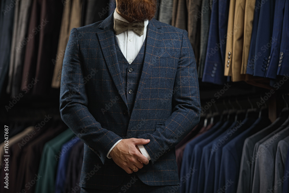 Businessman in classic vest against row of suits in shop Businessman in classic vest against row of suits in shop