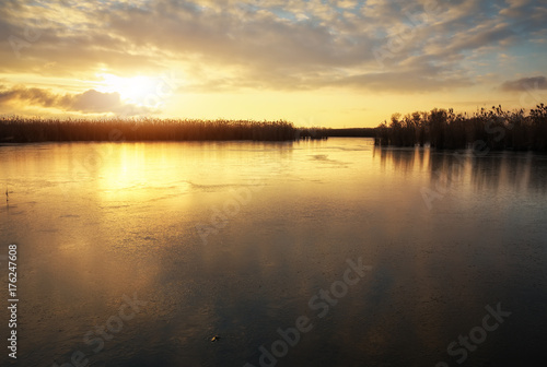 Winter landscape with frozen river and sunset sky. Composition of nature.