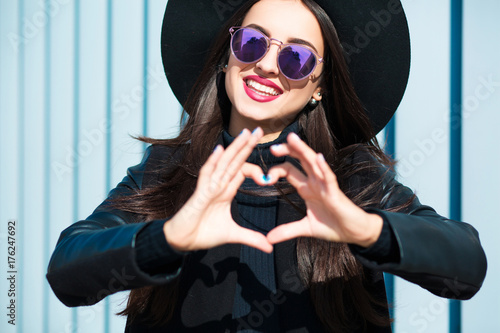 Happy young woman in glasses making a heart shape with her hands
